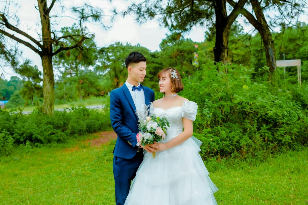 Bride and groom posing together outdoors at a wedding venue, holding hands and laughing naturally in soft golden-hour light