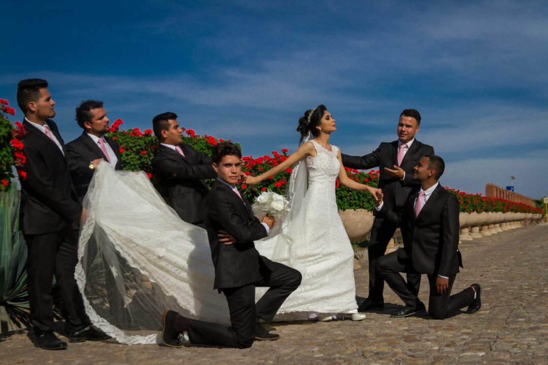 Bridal party walking together down a garden path, bridesmaids in matching dresses holding bouquets, laughing naturally