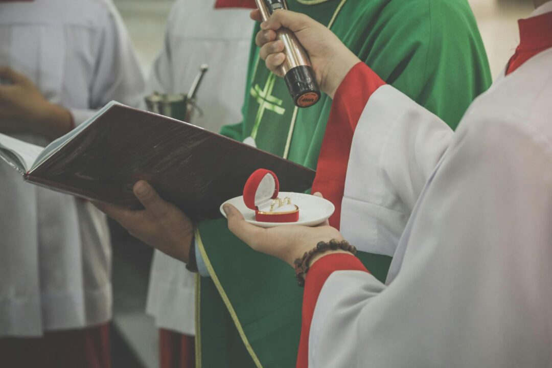 Intimate view of a wedding ceremony with rings held by priest in church.
