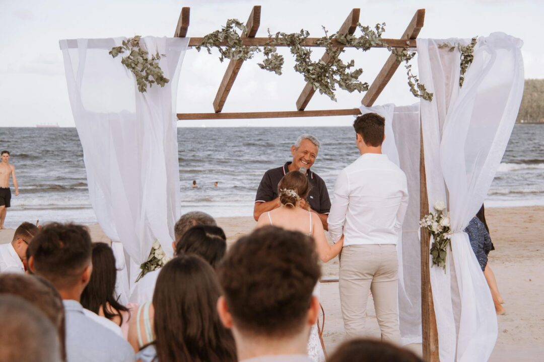 Barefoot couple at beach wedding under driftwood arch
