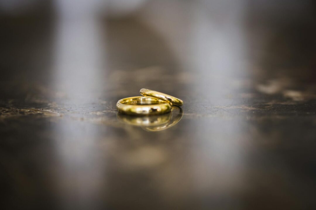 Close-up of two gold wedding bands resting on a soft cream fabric surface, natural light