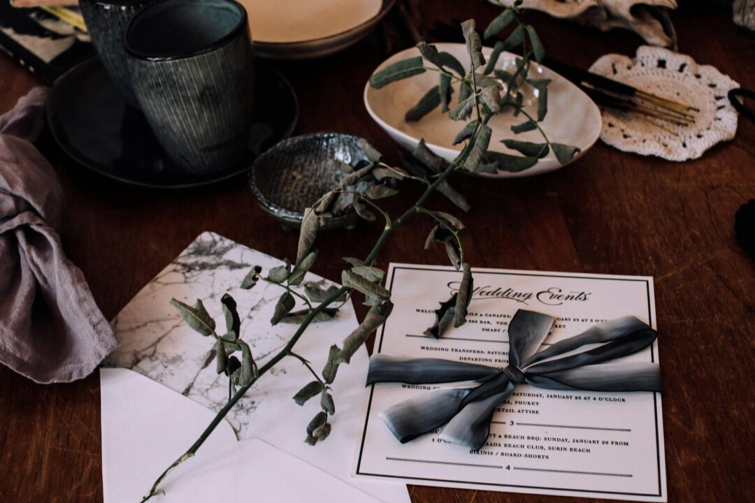 Paperlust wedding invitation suite flatlay with vellum belly band and wax seal, dried baby's breath, neutral tones, outstanding composition;