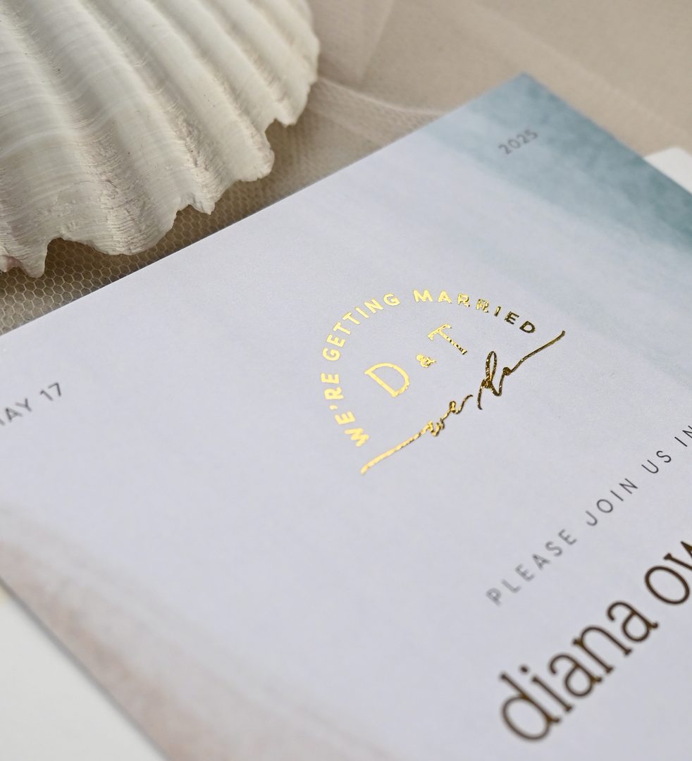Paperlust invitation, Beautiful close-up detail shot of a wedding invitation featuring gold foil stamping on a soft watercolor background