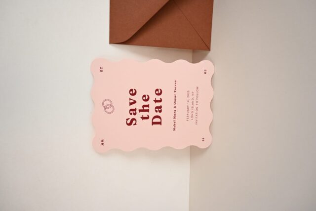 Paperlust invitation, Beautifully styled save-the-date card with wavy scalloped edges in blush pink with deep red typography