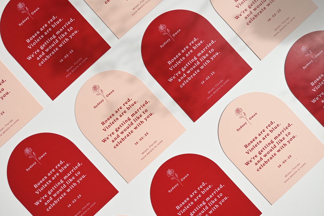 Paperlust invitation, Beautifully styled flat lay of arch-shaped wedding invitations in a striking red and blush pink color scheme with a playful roses-are-red poem. Miami