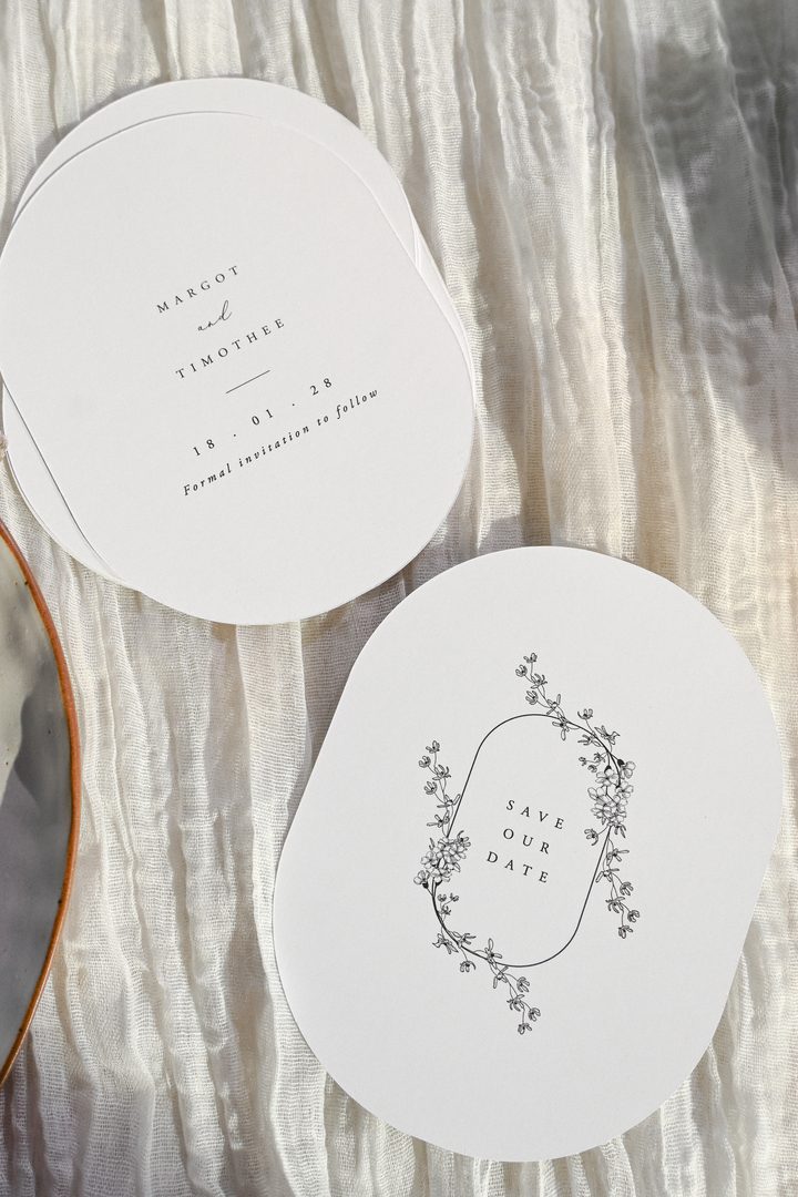 Paperlust invitation, Beautifully styled save-the-date cards in a minimalist circular design on soft white fabric. Elegant typography with delicate floral illustration