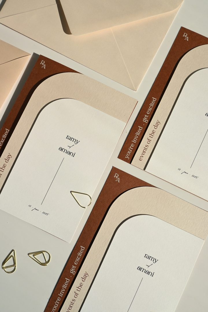 Paperlust invitation, Beautifully styled suite display featuring elegant arch-shaped wedding invitations for 'Ramy & Amani' with terracotta and cream color palette