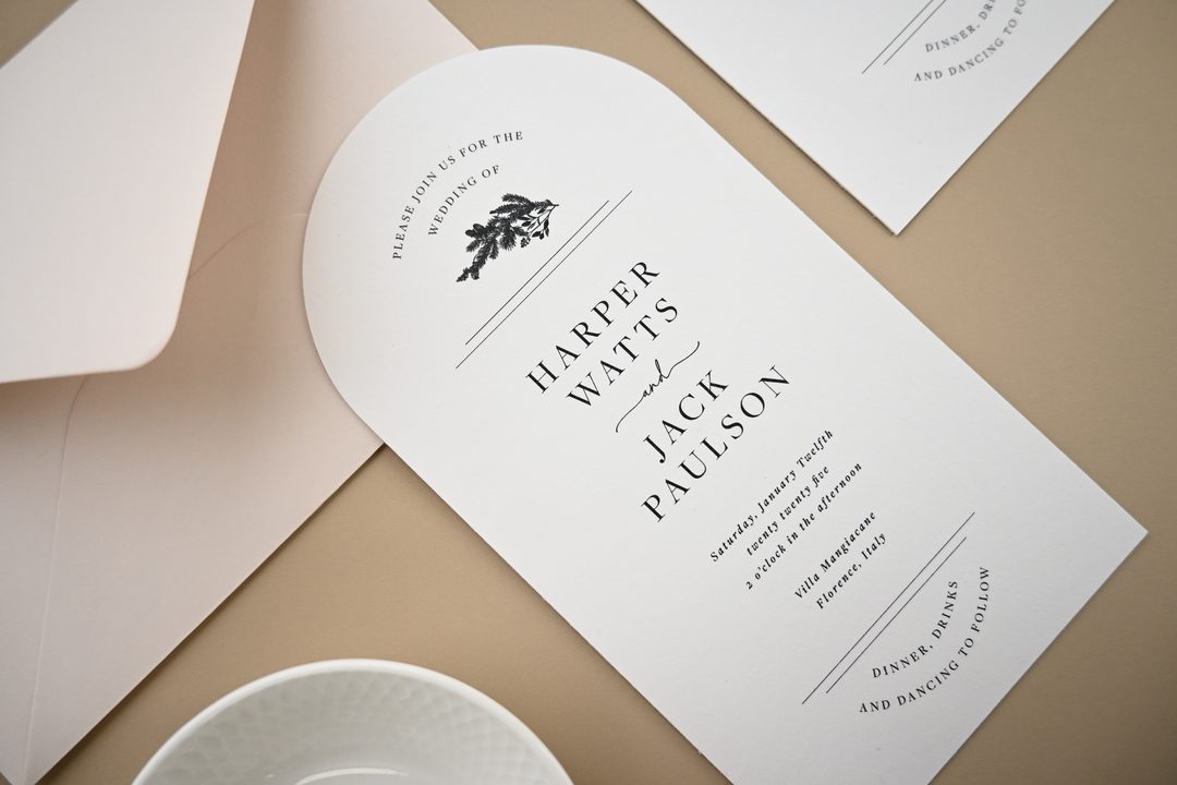 Paperlust invitation, Beautifully styled wedding invitation suite featuring arch-shaped cards with elegant typography. The muted beige/tan background