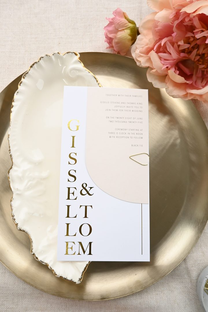 Paperlust invitation, Beautifully styled wedding invitation with gold foil typography on a gold tray with pink florals. Modern elegant design with strong visual appeal and excellent lighting.