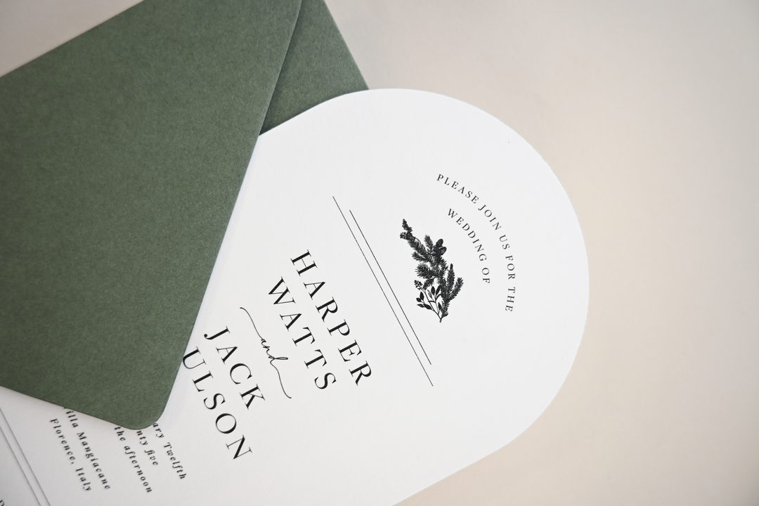 Paperlust invitation, Beautifully styled wedding invitation with arch-shaped card and olive green envelope. Elegant typography with botanical illustration