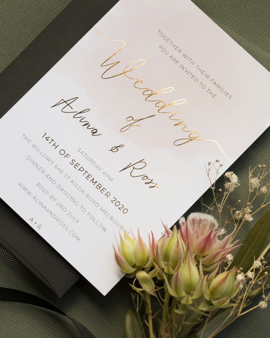 Paperlust invitation, Beautifully styled wedding invitation flatlay with gold foil calligraphy and dried florals. Contains Australian identifier 'St Kilda Road Melbourne' as the venue address.
