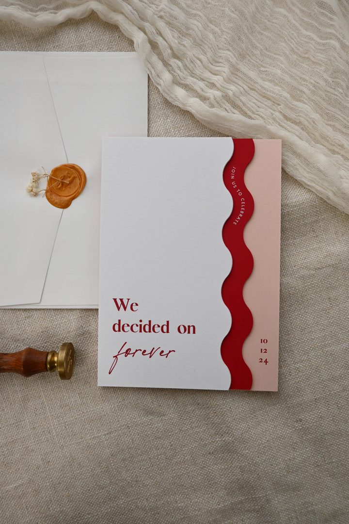 Paperlust invitation, Beautifully styled wedding invitation flatlay featuring a modern wavy-edge design with red and blush tones