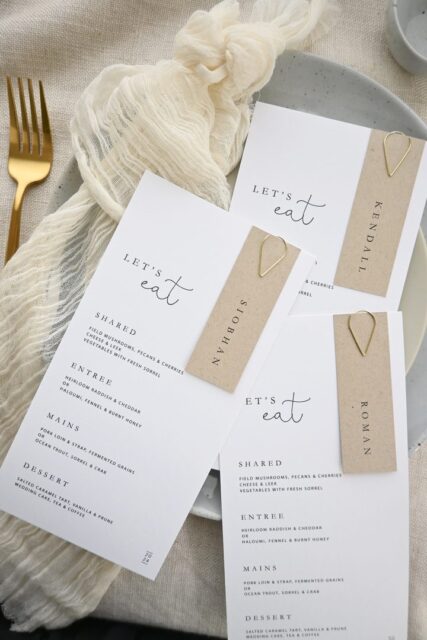 Paperlust menu, Beautifully styled flatlay of wedding menus with kraft paper name place cards and gold heart clips