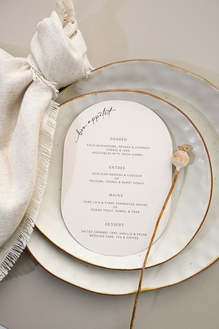 Paperlust program, Beautifully styled wedding menu on artisan ceramic plates with linen napkin and dried poppy stem. Exceptional composition with soft