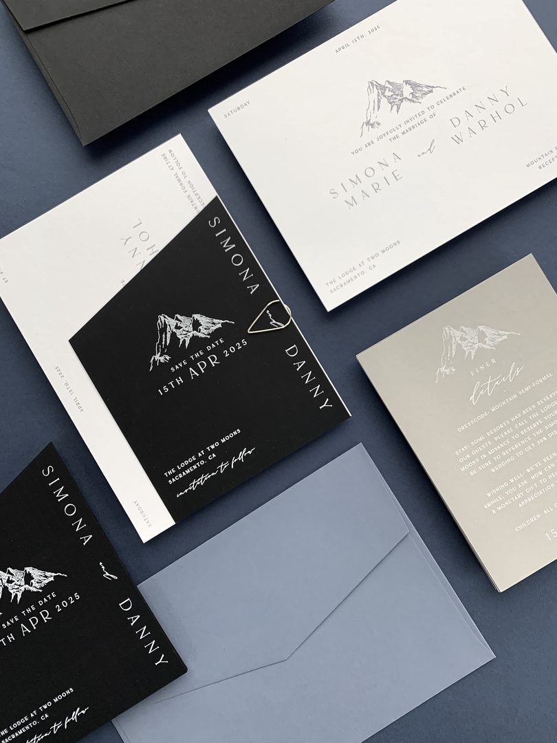 Modern monochrome save the date suite in black, cream and grey with a fine-line mountain illustration, styled on a slate-blue background