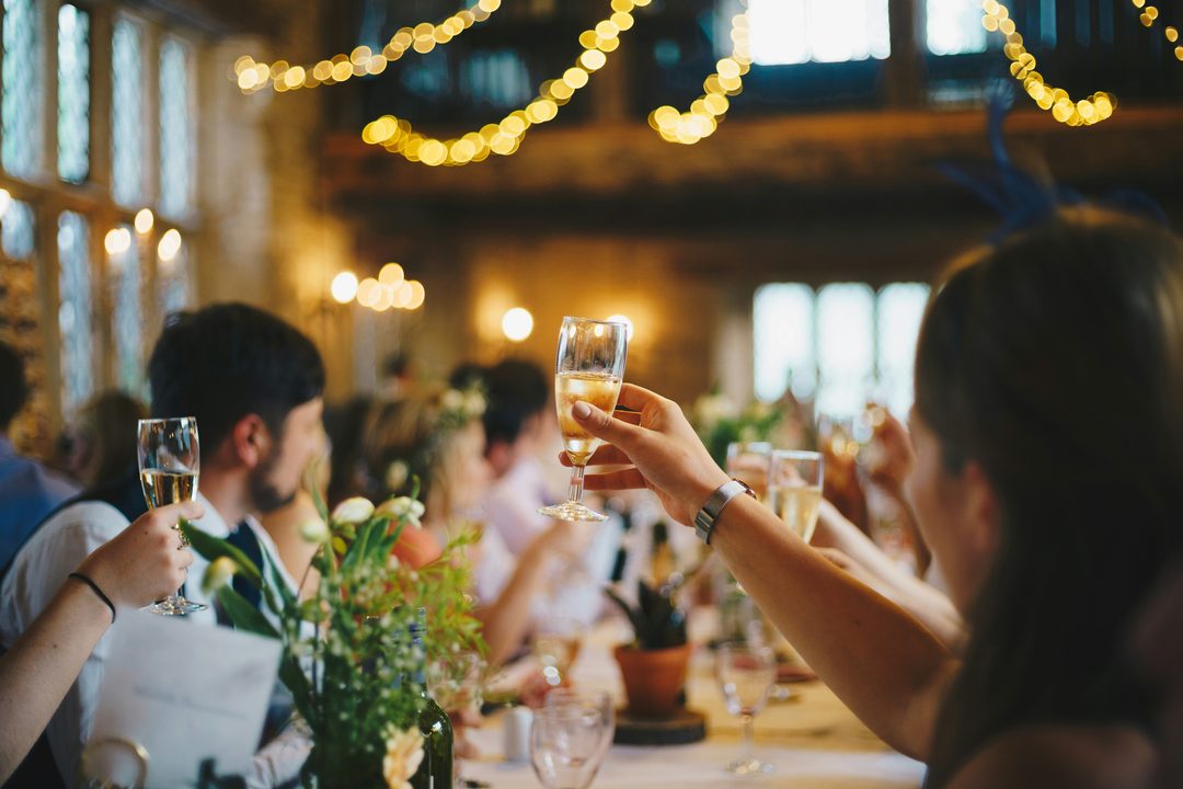 Guests raising wine glasses for a toast at a wedding dinner