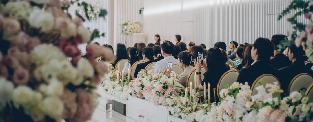 Wedding guests seated for a reception dinner among floral arrangements