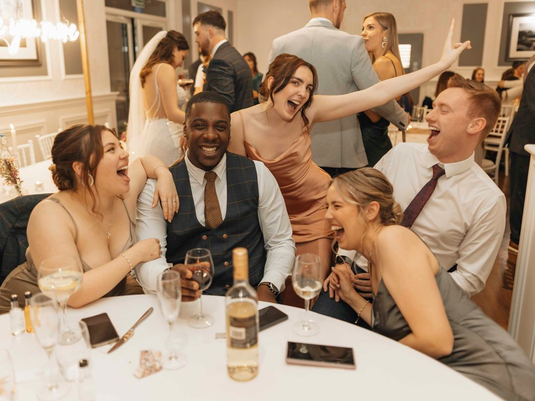 Wedding guests seated together around a white reception table