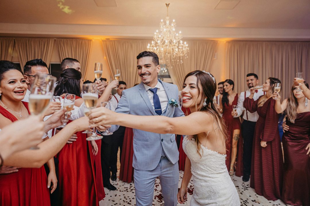 Couple and guests raising their glasses for a wedding toast indoors