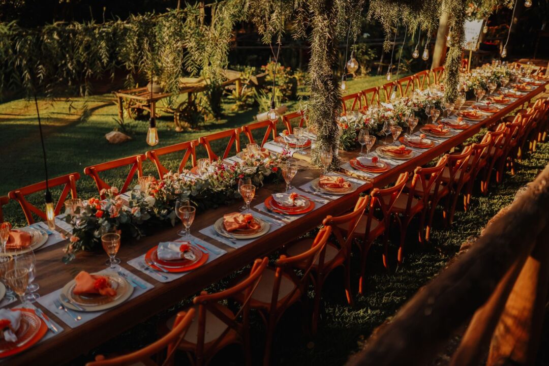 Long festive wedding reception banquet table filled with guests laughing and raising glasses, warm candlelight and...