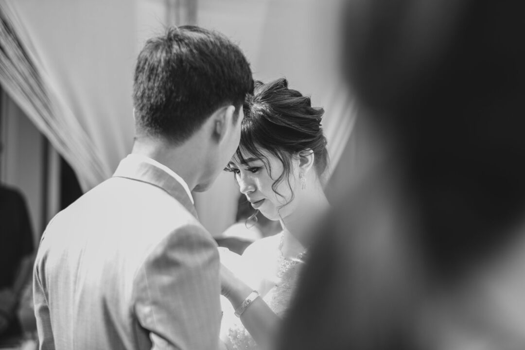 Bride and groom sharing a quiet emotional moment during a small intimate wedding ceremony with just close family seated...