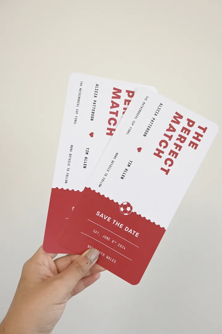 Paperlust The Perfect Match funny save the date, football ticket-style die-cut cards in red and white held in hand
