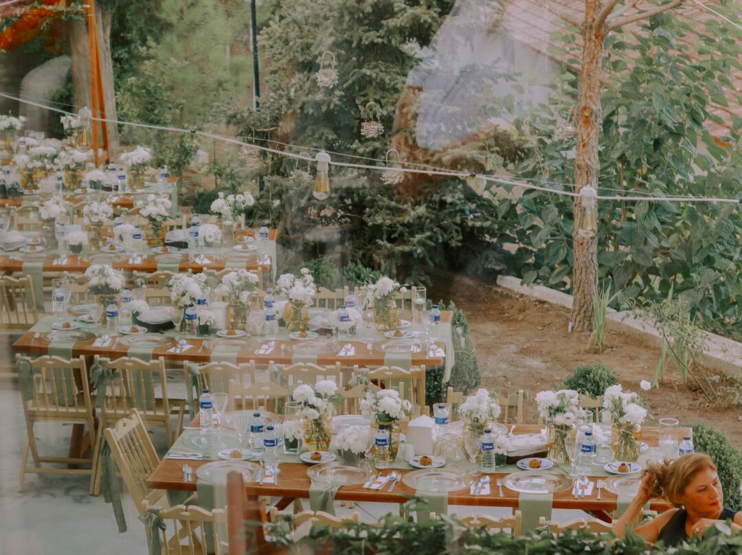 Beautifully set long dining table for 24 guests outdoors at a vineyard micro wedding, with tapered candles, small floral...