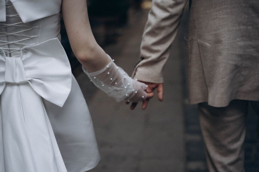 Bride and groom holding hands during an intimate micro wedding ceremony in a light-filled converted loft, 20 guests...