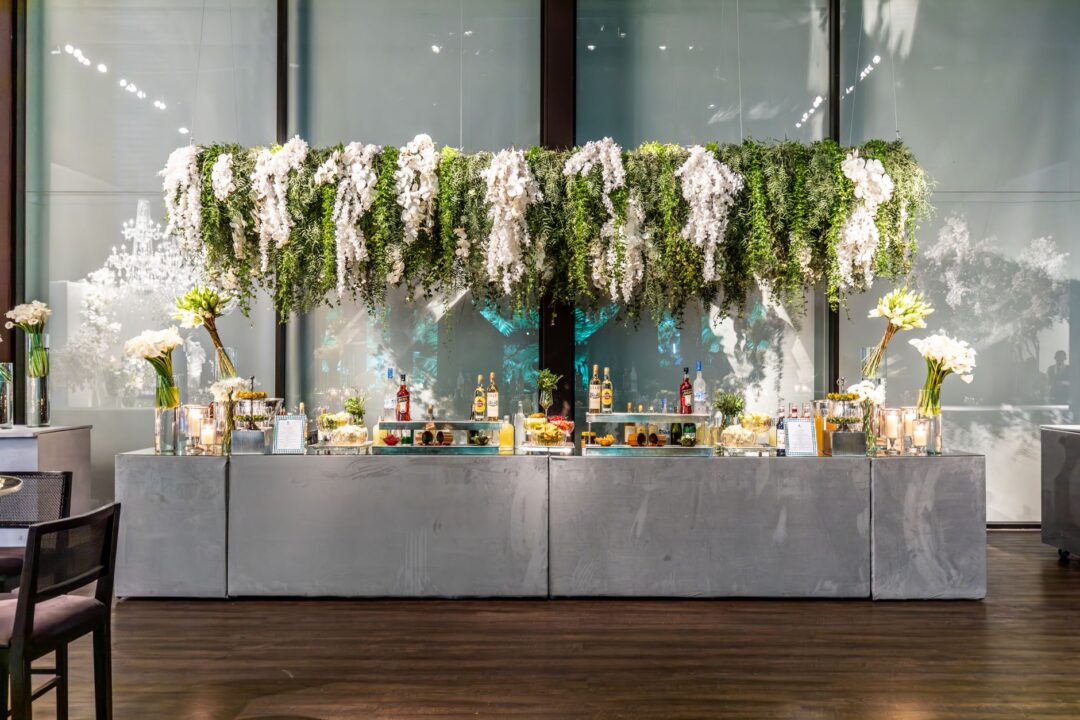 Beautifully styled wedding bar setup with floral arrangements, champagne bottles in ice, and crystal glassware on a...