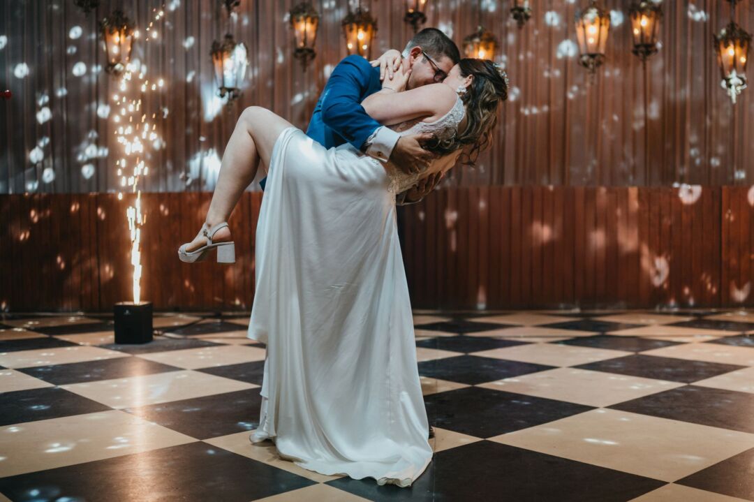 Black-and-white checkered vinyl dance floor set up in a hotel ballroom for a wedding, couples dancing in formal attire...