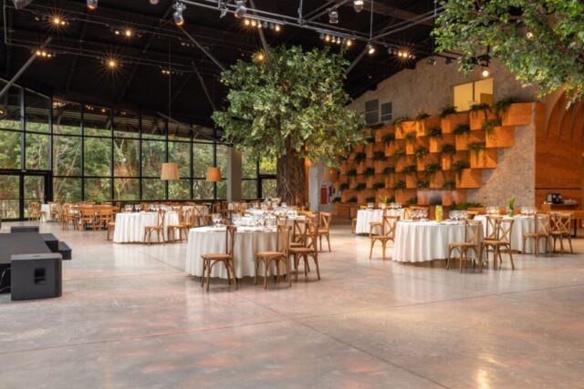 Polished light oak parquet dance floor crowded with wedding guests dancing at a golden-hour outdoor reception under...