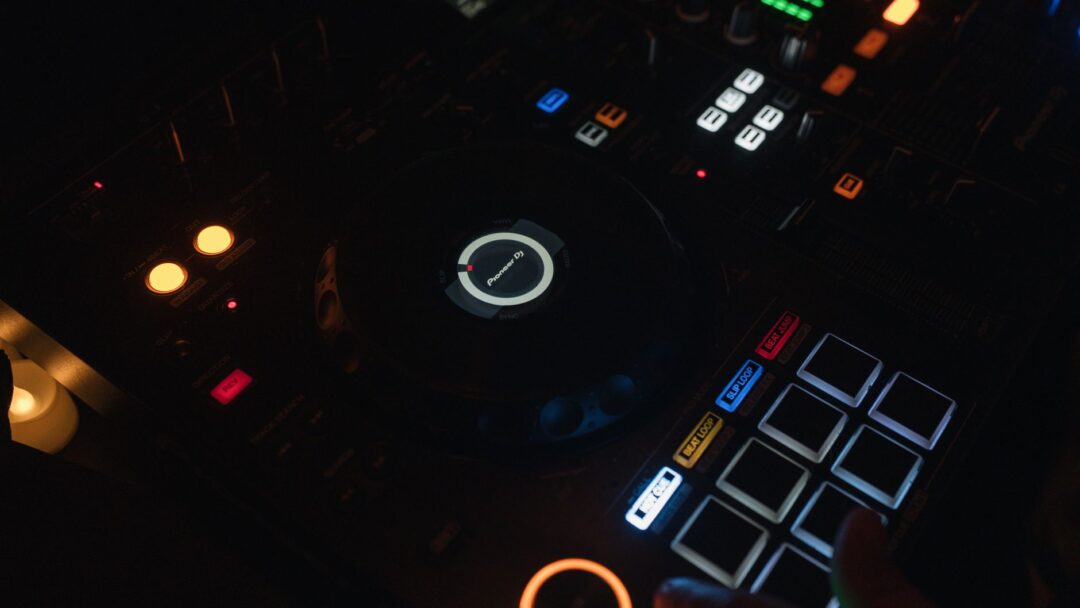 Wedding DJ uplighting setup casting amber and purple light on a barn venue reception space, showing the dance floor and...