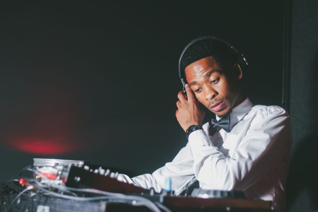 Wedding DJ in formal attire mixing at the decks with headphones at a reception
