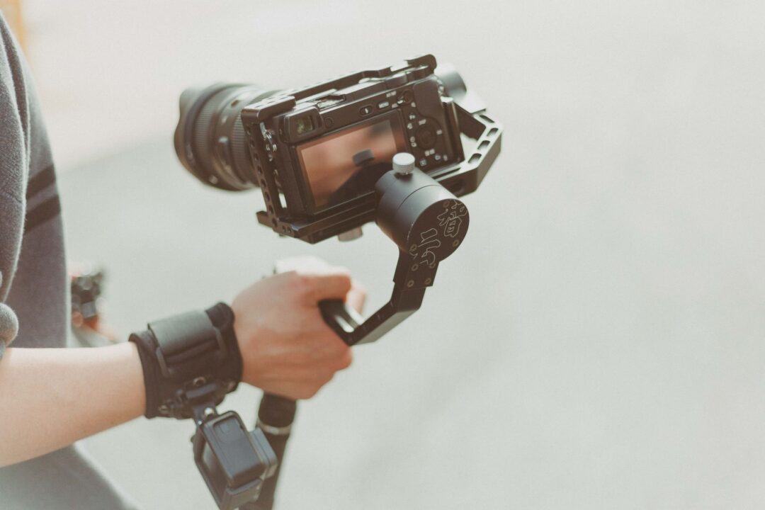 Wedding videographer setting up a gimbal stabilizer at the end of a floral-decorated ceremony aisle before guests are seated