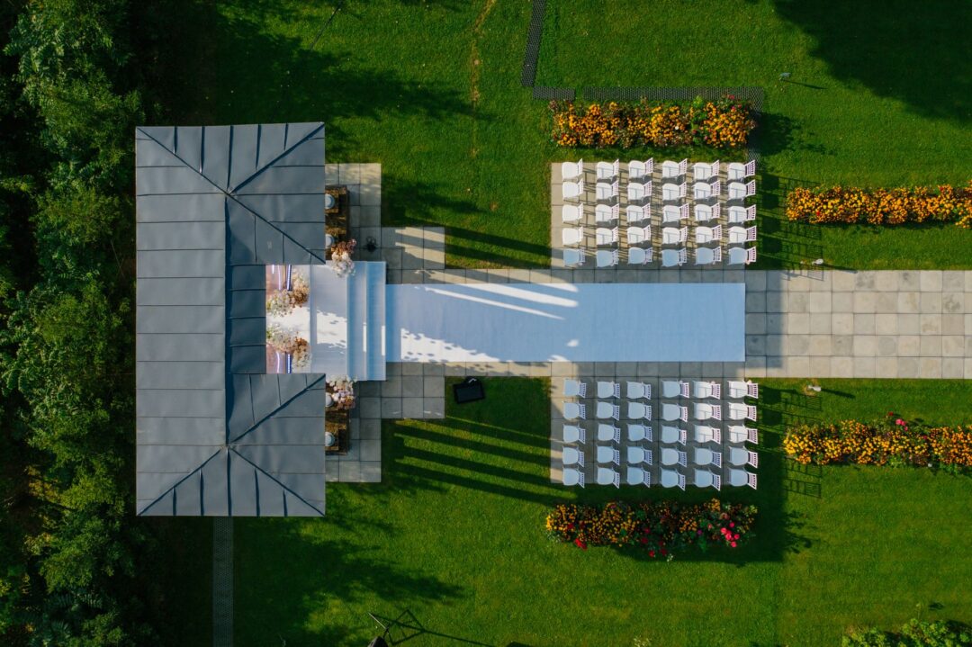 Aerial drone footage perspective of a wedding ceremony at an outdoor garden venue surrounded by mature trees