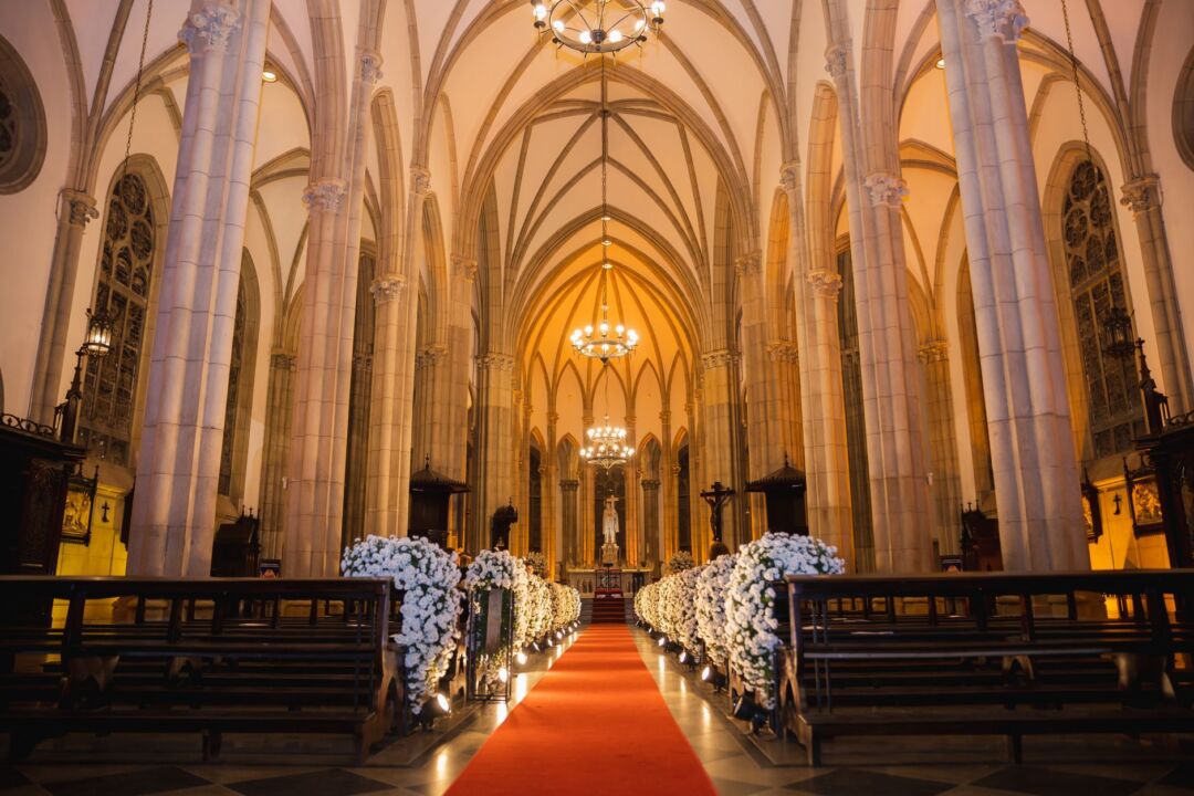 Wedding lighting professional placing and aiming LED uplighting canisters along the perimeter of an empty ballroom, warm...