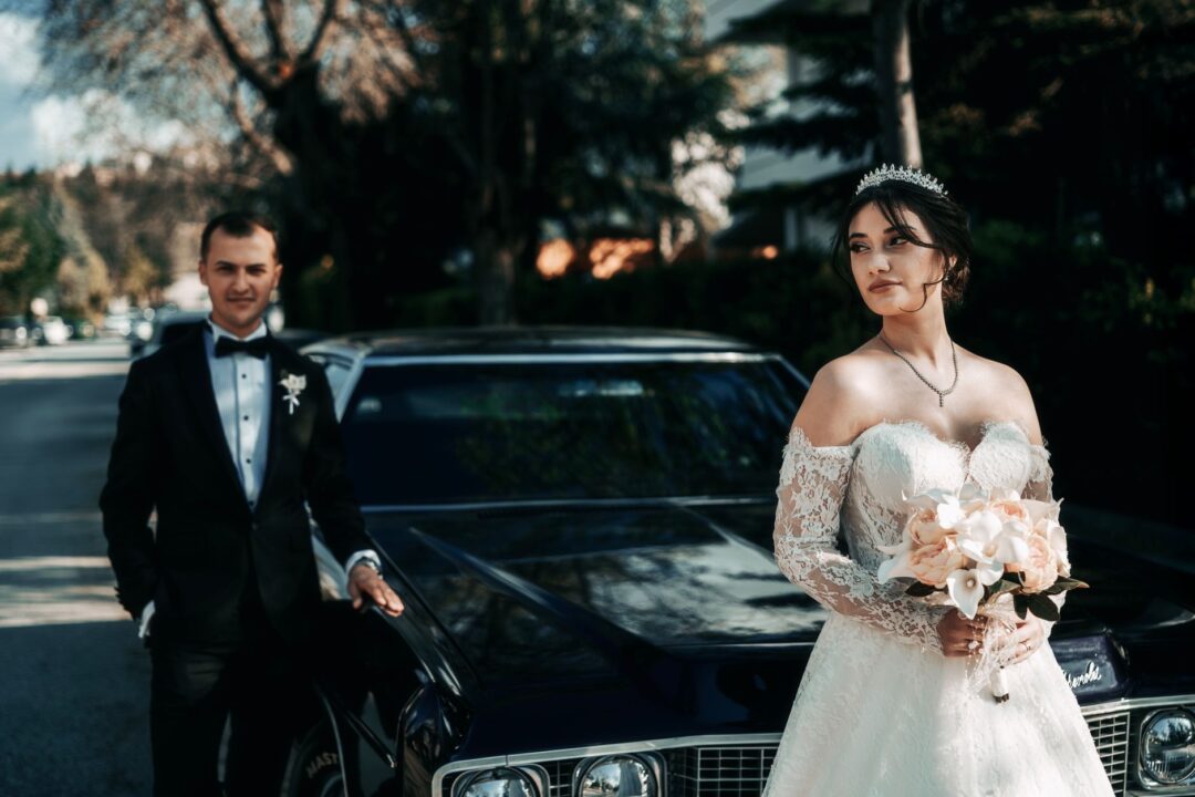 Bride and groom beside a classic wedding car