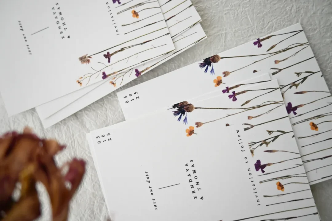 Paperlust Flora save the date cards with pressed wildflower illustrations fanned out on textured paper