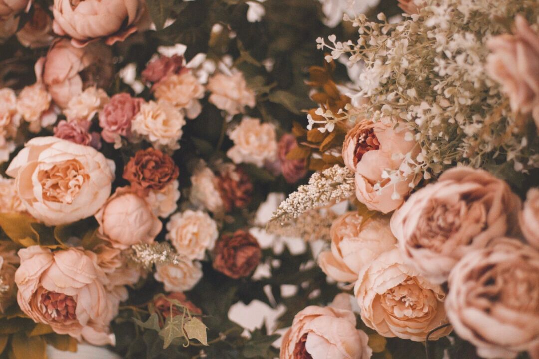 Close-up flat lay of a high-quality silk peony and rose bridal bouquet with ribbon stems on white linen, realistic petal...