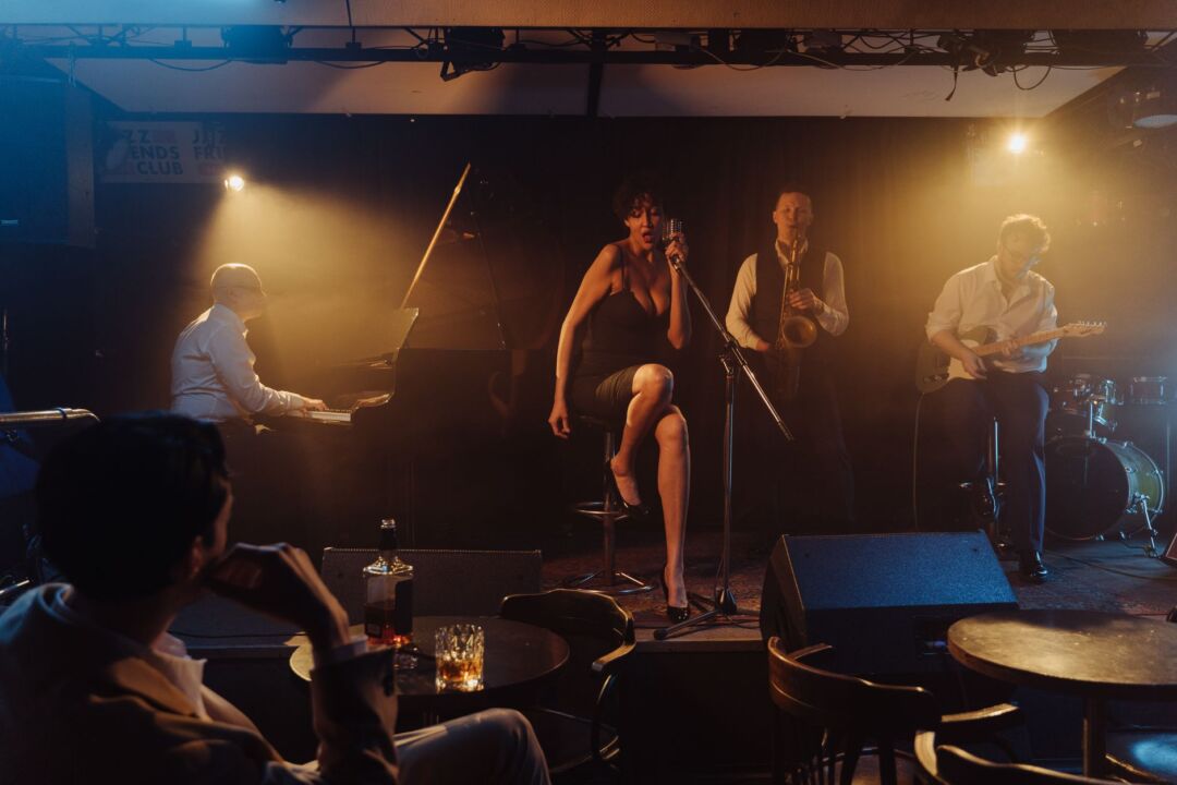 Four-piece jazz band performing at a wedding cocktail hour in a warm, intimate ballroom, musicians in formal attire with...
