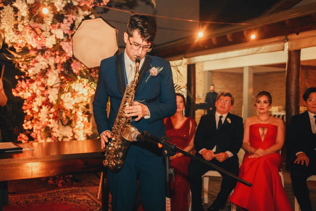 Wedding reception in full swing, a five-piece live band performing on a lit stage while guests crowd the dance floor,...