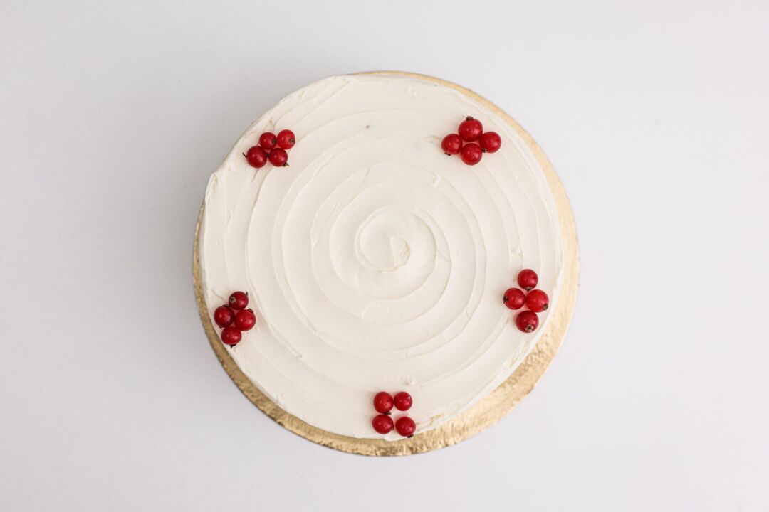 Close-up overhead view of a round white wedding cake tier being cut into neat slices by a caterer in white gloves, a...