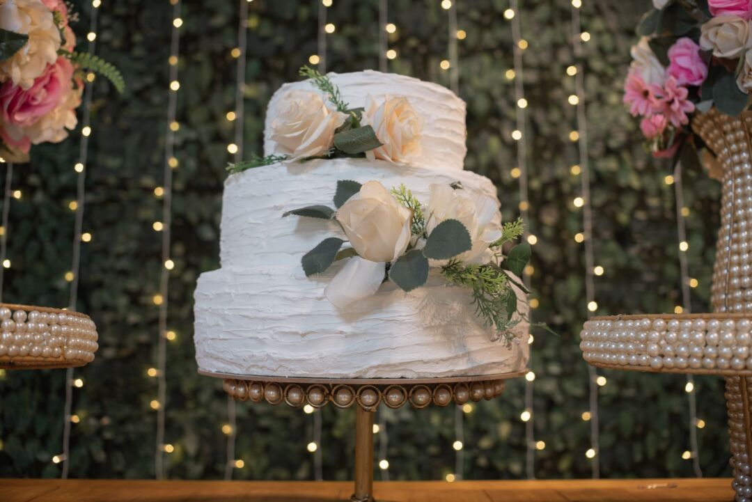 Side-by-side styled photo showing a 3-tier round white wedding cake on the left and a 4-tier square fondant wedding cake...