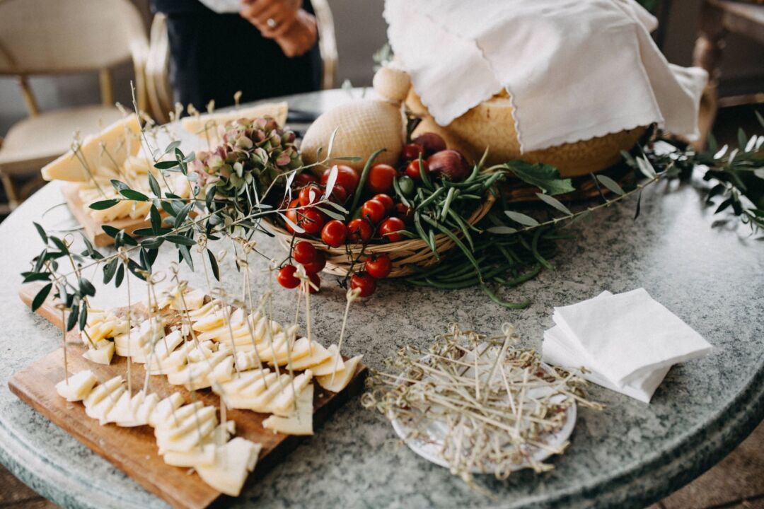 Elegantly arranged wedding appetizer display on a marble surface with bruschetta, charcuterie, fresh herbs, and small...