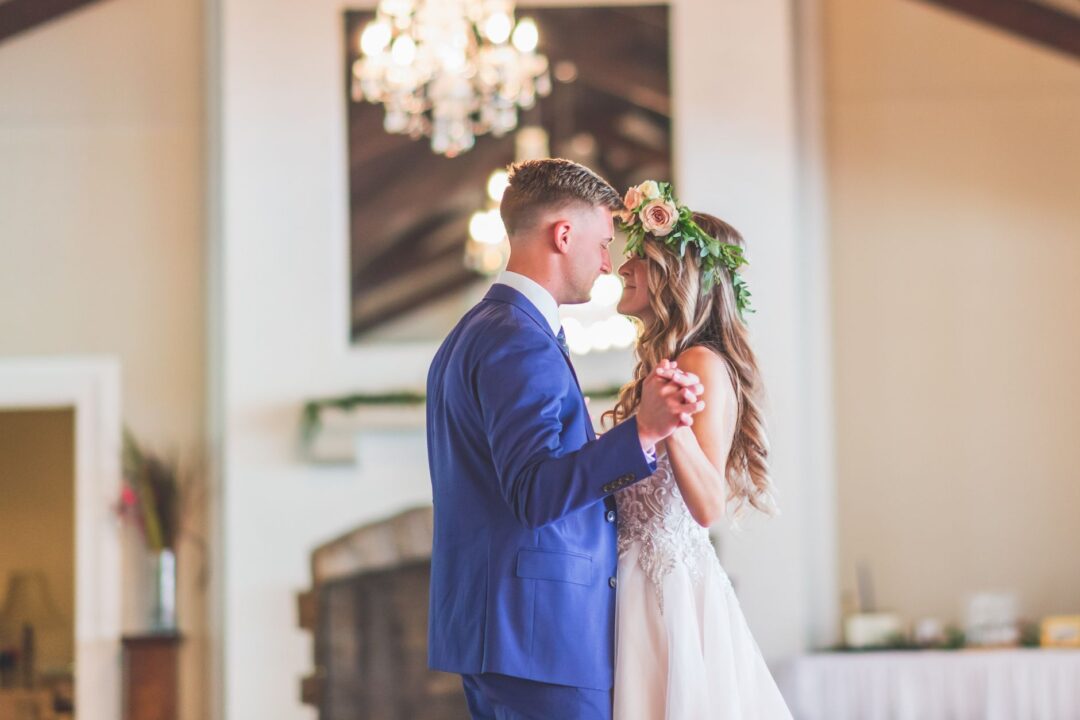 Couple sharing their first dance at a reception while a photographer shoots from one side and a videographer with a...