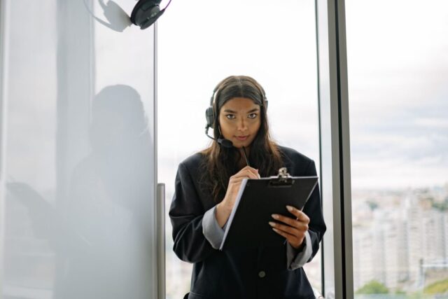 Wedding COORDINATOR at work, wearing a headset/earpiece, holding a clipboard/checklist, and directing at a wedding venue