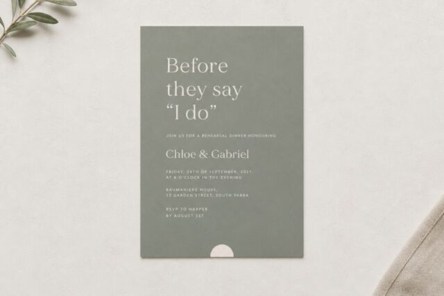 A sage green Paperlust Oliva rehearsal dinner invitation photographed flat from overhead on warm plaster.