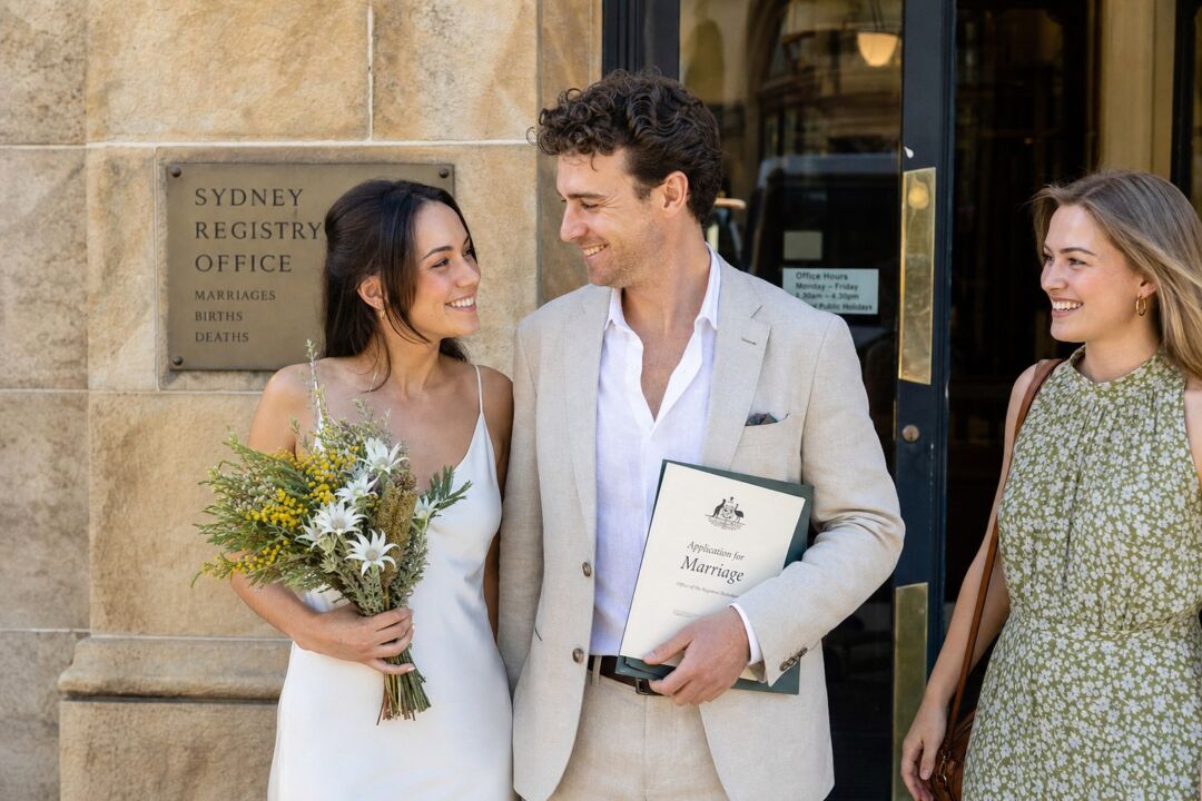 A couple in their late twenties standing together outside an Australian registry office on their wedding morning.