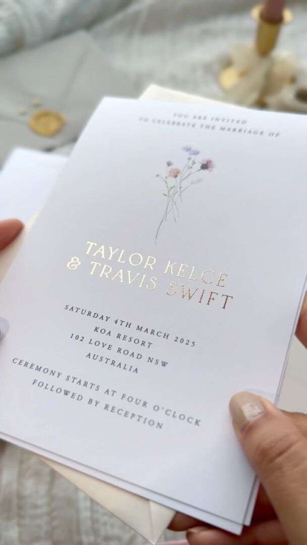 Wildest Dreams invitation with foil-printed floral details, held in hand.