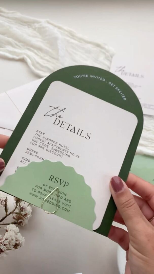 Die-cut arch-shaped invitation suite with forest-green and cream cards.
